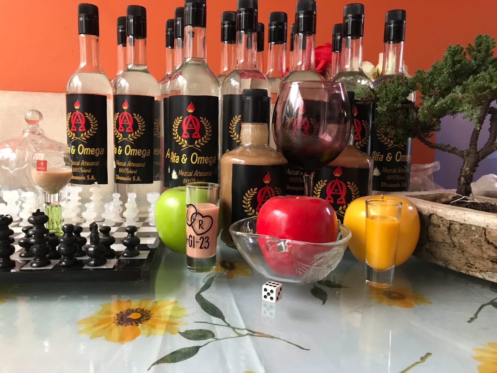 Varias botellas y presentaciones de mezcal ALFA & OMEGA en mesa decorada